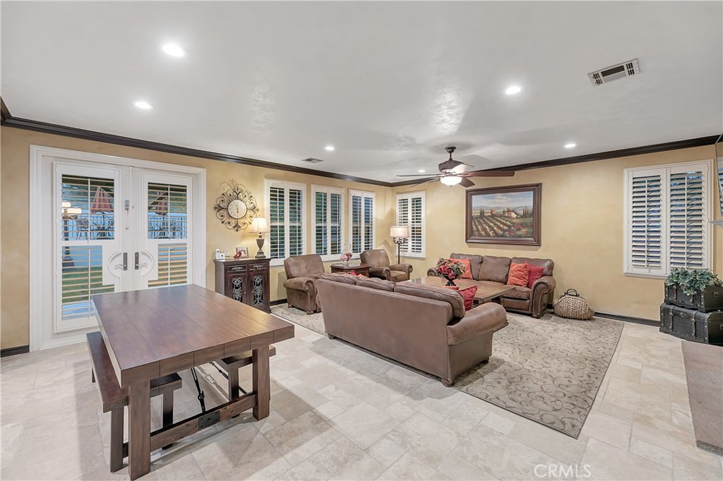 Furnished living room with a brown sectional, plantation shutters, and French doors.