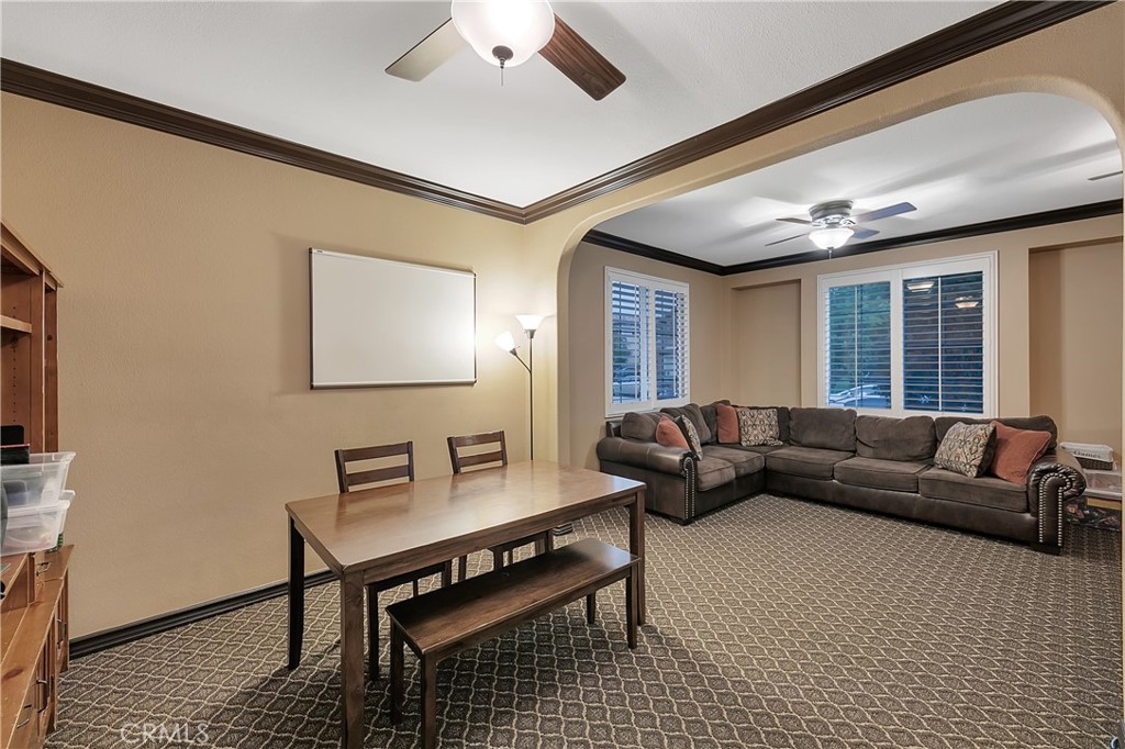 Furnished living room with a dark sectional, shuttered windows, and a wooden table with benches.