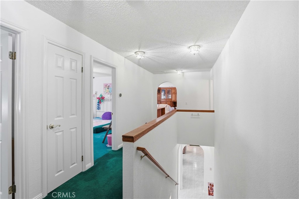 Upstairs hallway with green carpet and a wood-trimmed stair railing.
