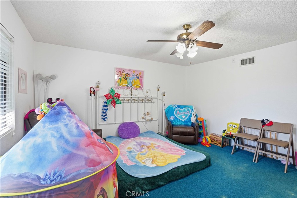 Children’s bedroom with teal carpet, a princess rug, and a colorful canopy play tent.
