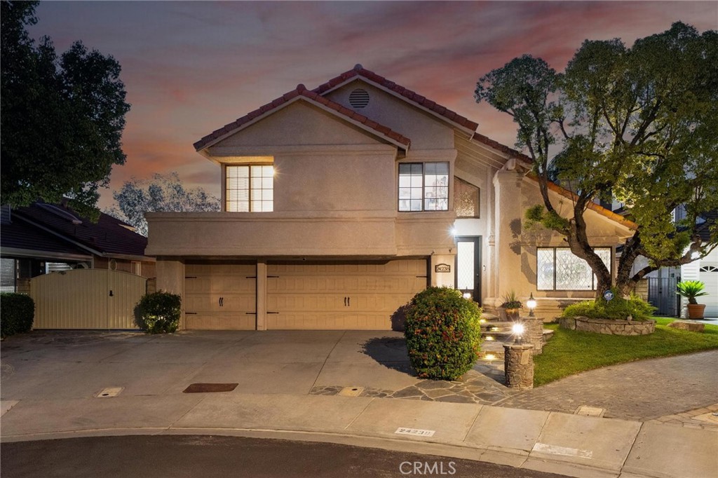 Two-story stucco home with a three-car garage and landscaped yard at dusk.