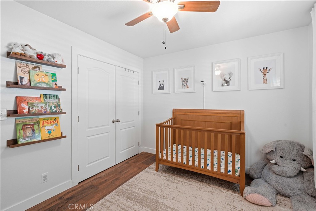 Nursery with a wooden crib, book shelves, framed animal prints, and a large plush elephant.