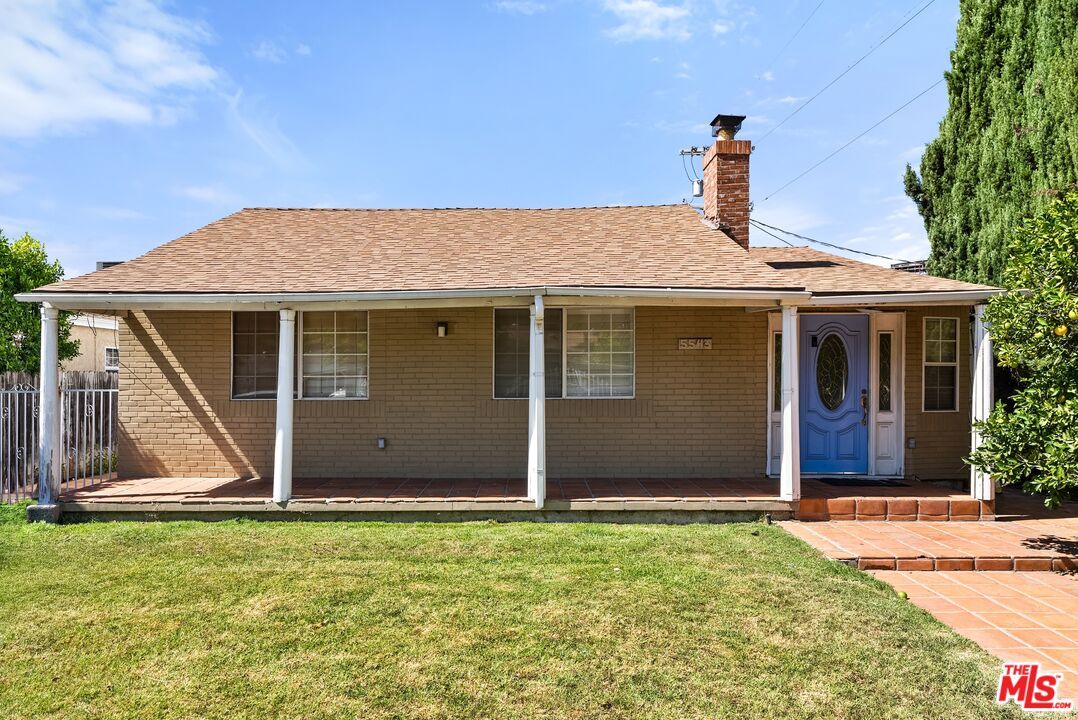 Single-story brick house with a covered porch, blue front door, and lawn.
