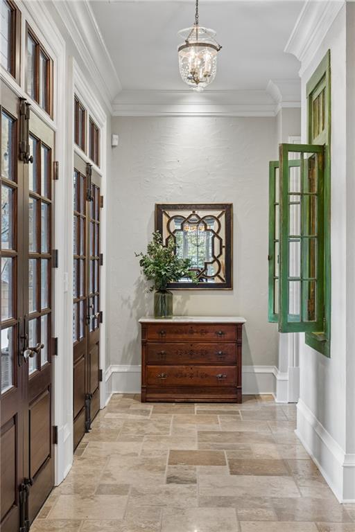 Entry hall with stone tile, dark wood doors, green shutters, and a wooden chest beneath a mirror.