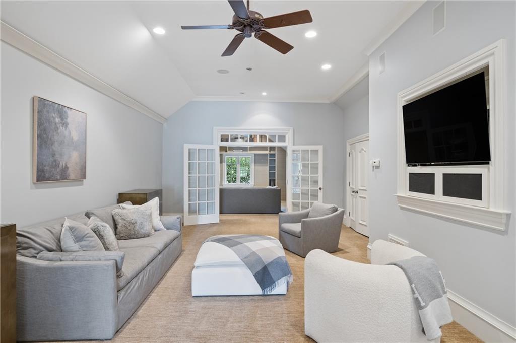 Staged living room with gray seating, a ceiling fan, and French doors to an adjoining room.