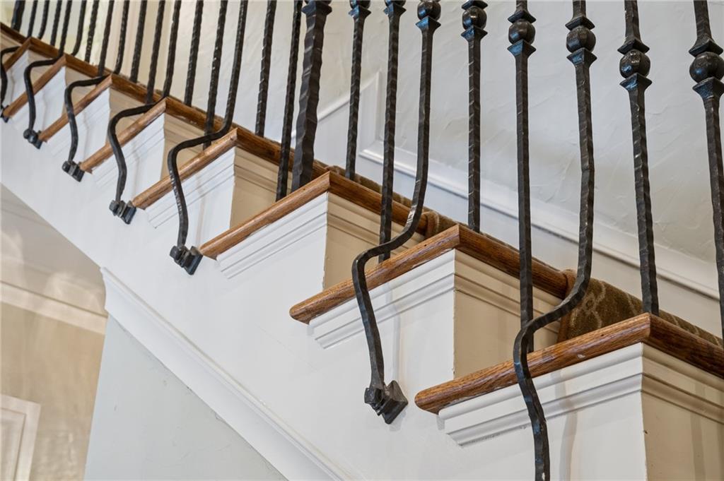 Interior staircase with wrought-iron balusters, polished wood handrails, and white trim.