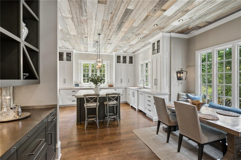 Bright kitchen with white cabinetry, wood plank ceiling, island, and adjoining dining nook.