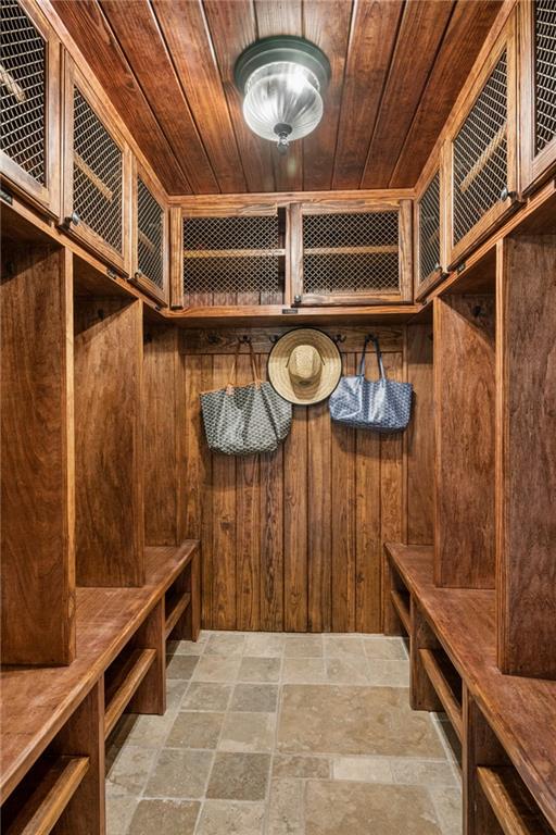 Wood-paneled walk-in closet with built-in cabinets, benches, and tiled flooring.