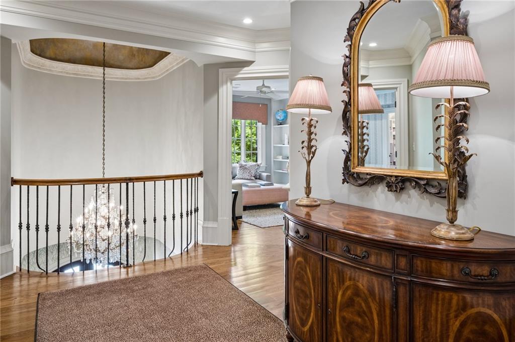 Upstairs landing with an ornate mirror and dresser, overlooking a chandelier below.