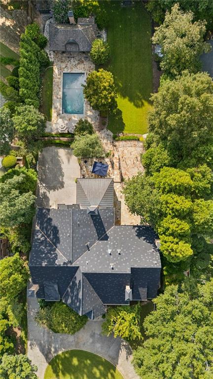 Aerial view of a large house, swimming pool, stone patio, and tree-lined lawn.