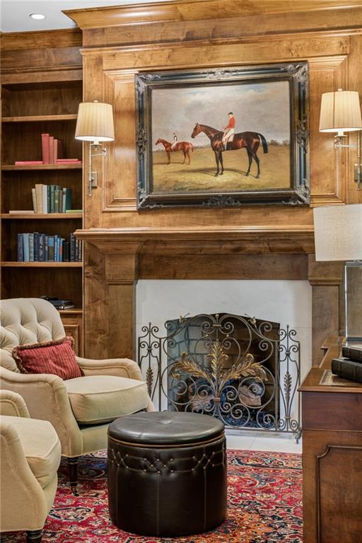 Living room with a wood-paneled fireplace, built-in bookshelves, and ornate metal screen.