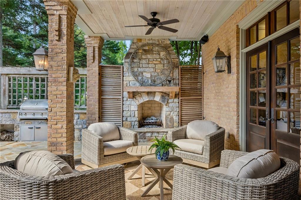 Covered patio with wicker seating, a stone fireplace, and a built-in grill.