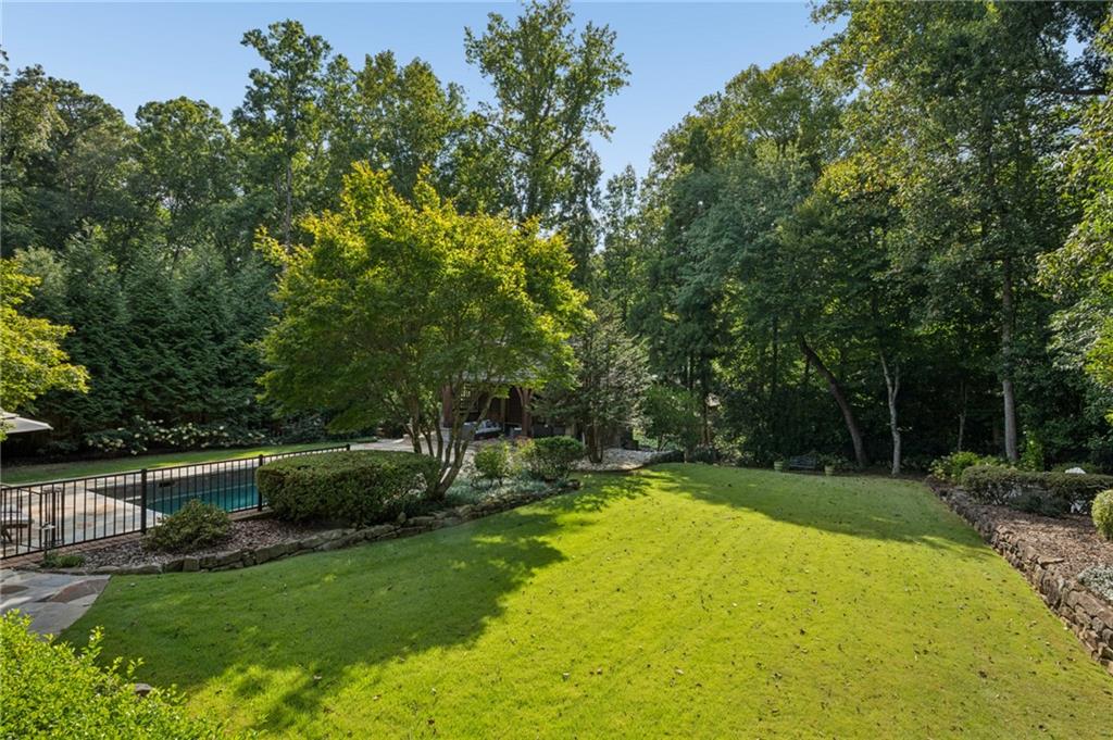 Backyard lawn with a fenced swimming pool and mature trees.