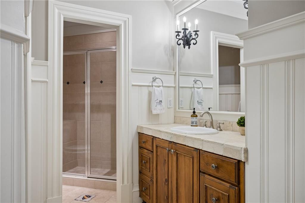 Bathroom with a glass-enclosed tiled shower and wood vanity beneath a large mirror.