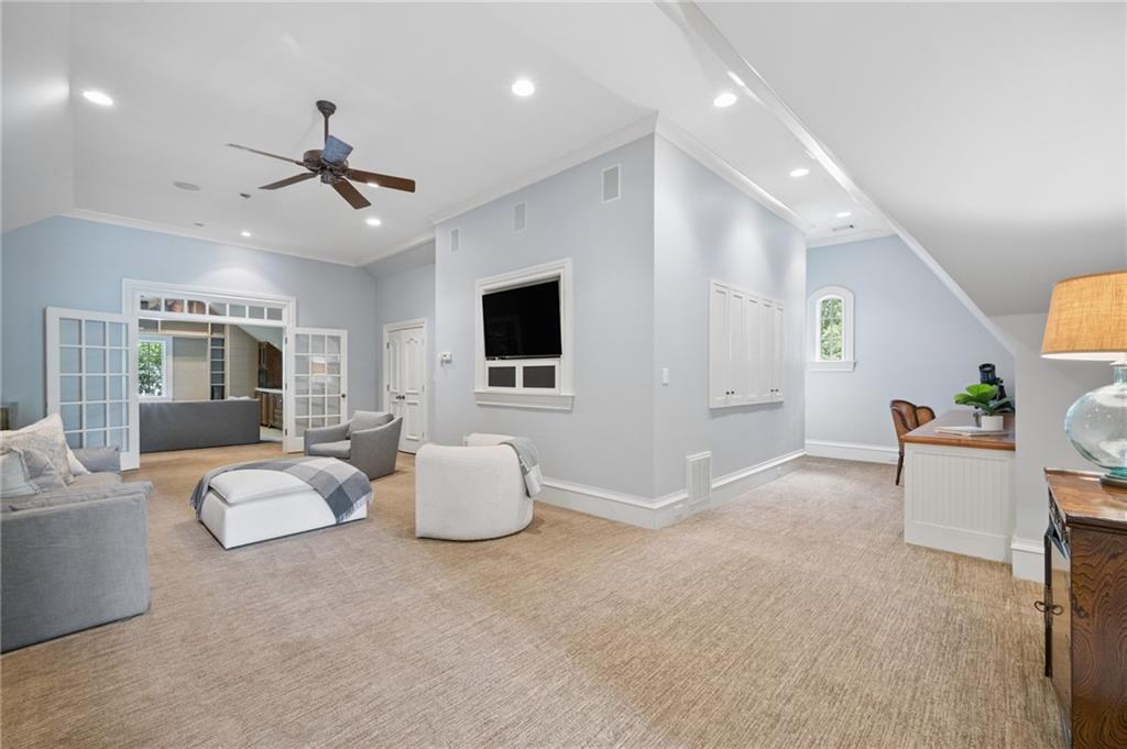 Furnished living room with French doors, built-in cabinets, and a ceiling fan.