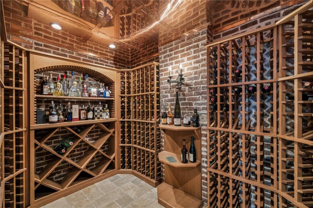 Wine cellar with brick walls, wooden bottle racks, a liquor shelf, and a small tasting counter.