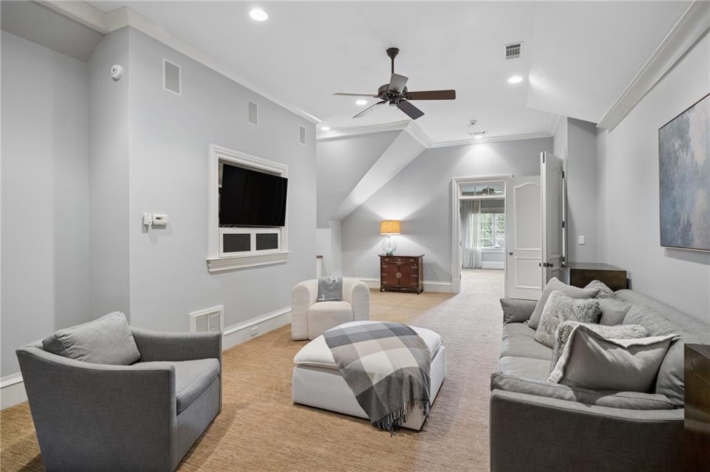 Living room with gray seating, a ceiling fan, and an open doorway to a bright adjoining room.