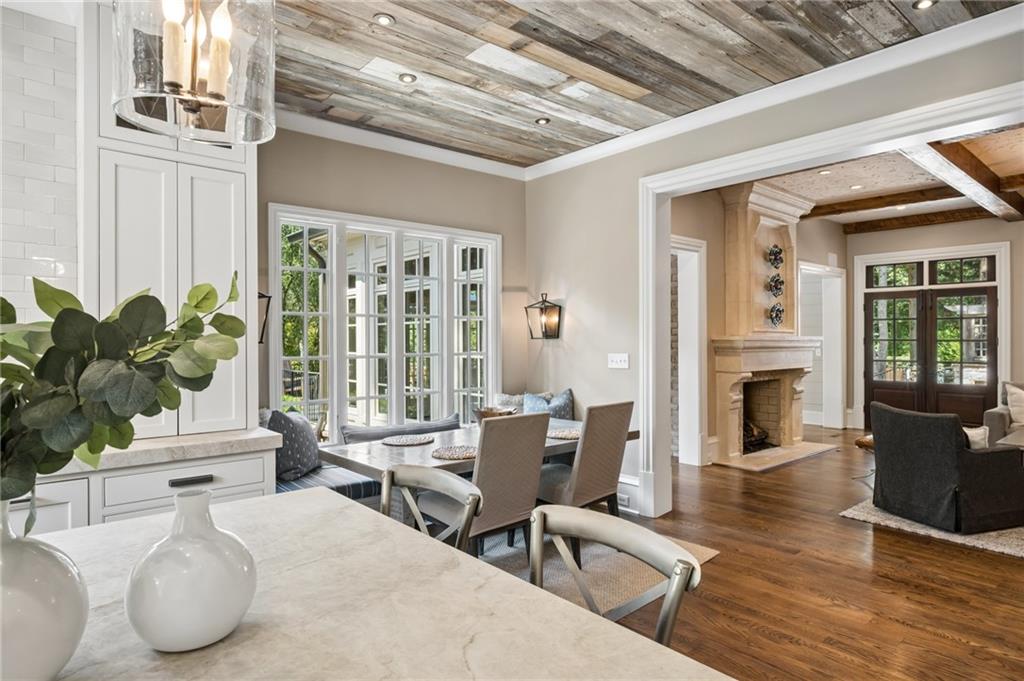 Open-plan kitchen and dining area with a stone island, wood-plank ceiling, and adjoining fireplace