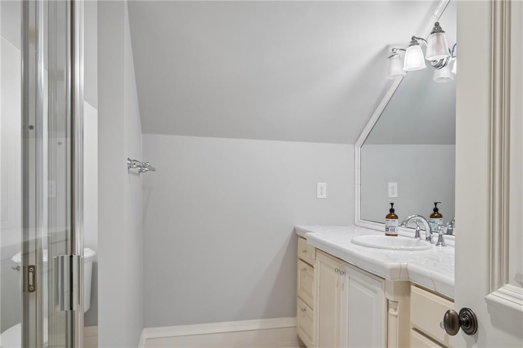 Bathroom with a glass shower and cream vanity topped by a large mirror.