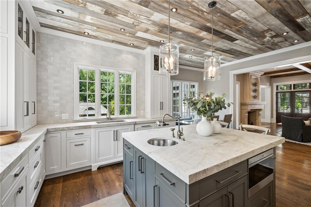 Kitchen with a large stone-topped island, white cabinets, and a reclaimed wood ceiling.