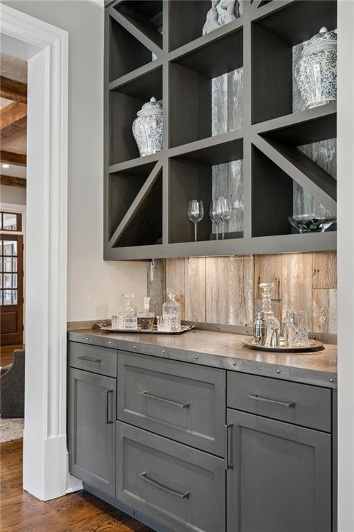 Built-in wet bar with geometric shelving, glassware, and a wood backsplash.