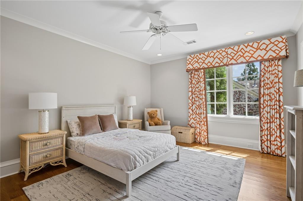 Bedroom with a white bed, orange patterned curtains, and a sunlit window.