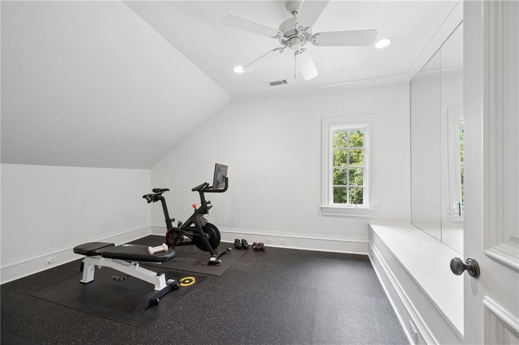 Home gym with a stationary bike, weight bench, and mirrored wall panels.