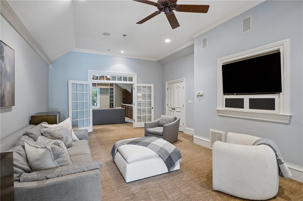 Living room with gray seating, a large ottoman, and open glass-paneled French doors.