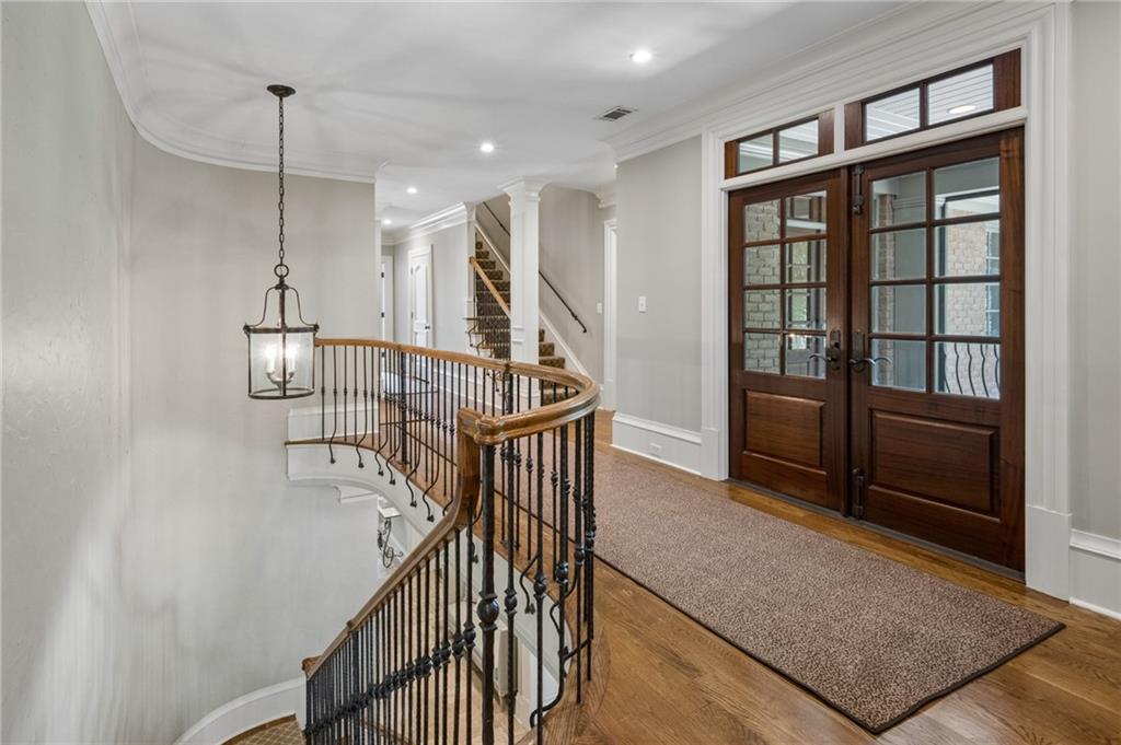 Entry hall with glass-paneled wood doors and a curved staircase with iron balusters.