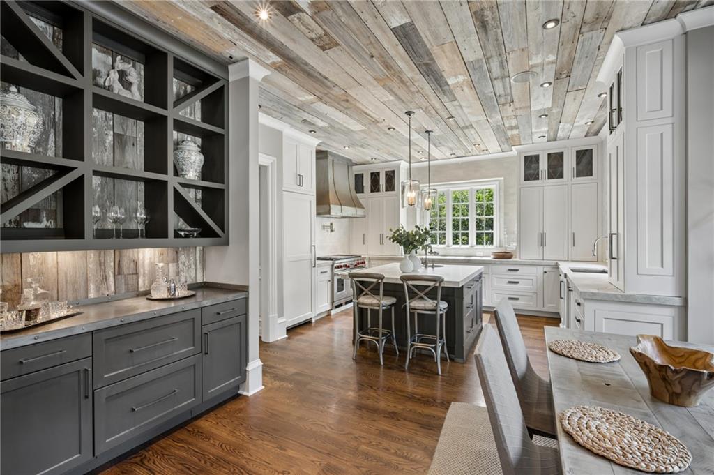 Kitchen with white cabinetry, dark gray island, wood-plank ceiling, and hardwood floors.