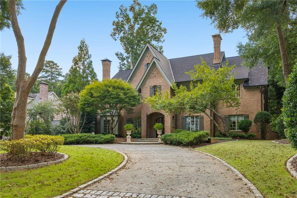Two-story brick house with front gables, an arched entry, and a curved driveway.