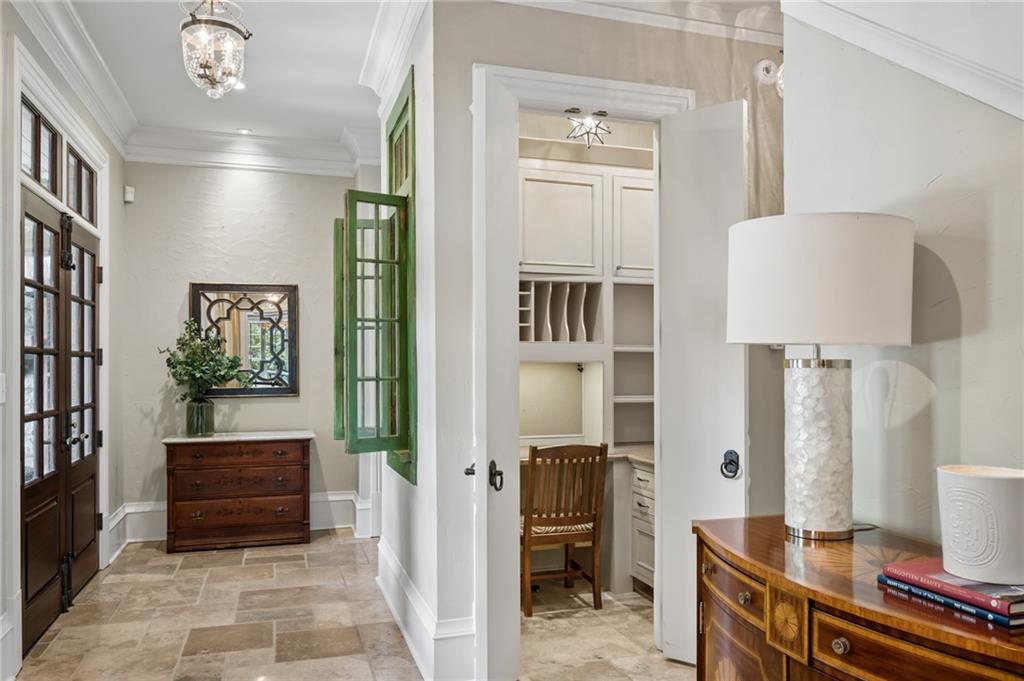 Entry hall with tiled floors, green shutters, wooden chest, and built-in desk nook.