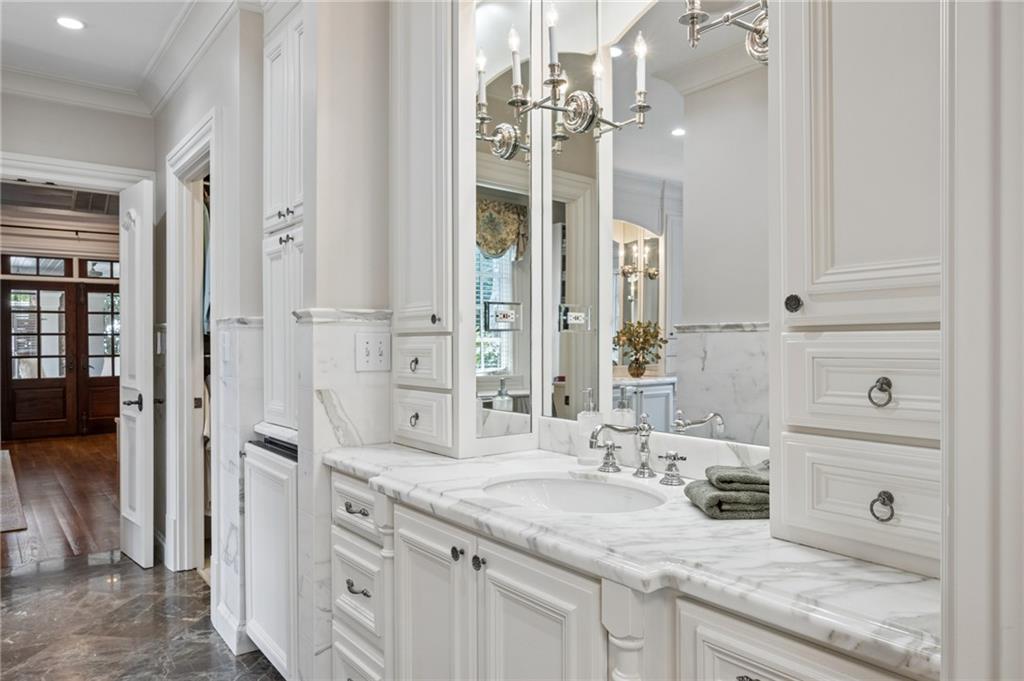Bathroom vanity with a marble countertop, mirrored cabinets, and polished marble flooring.