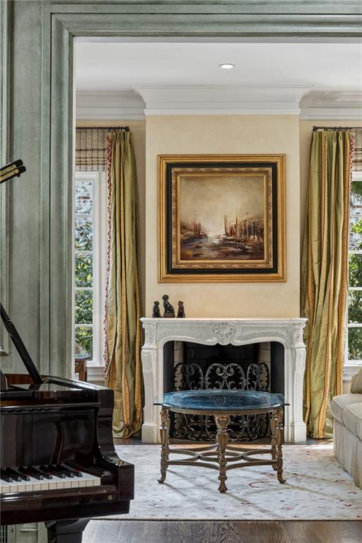 Living room with a carved white fireplace, black grand piano, and tall curtained windows.