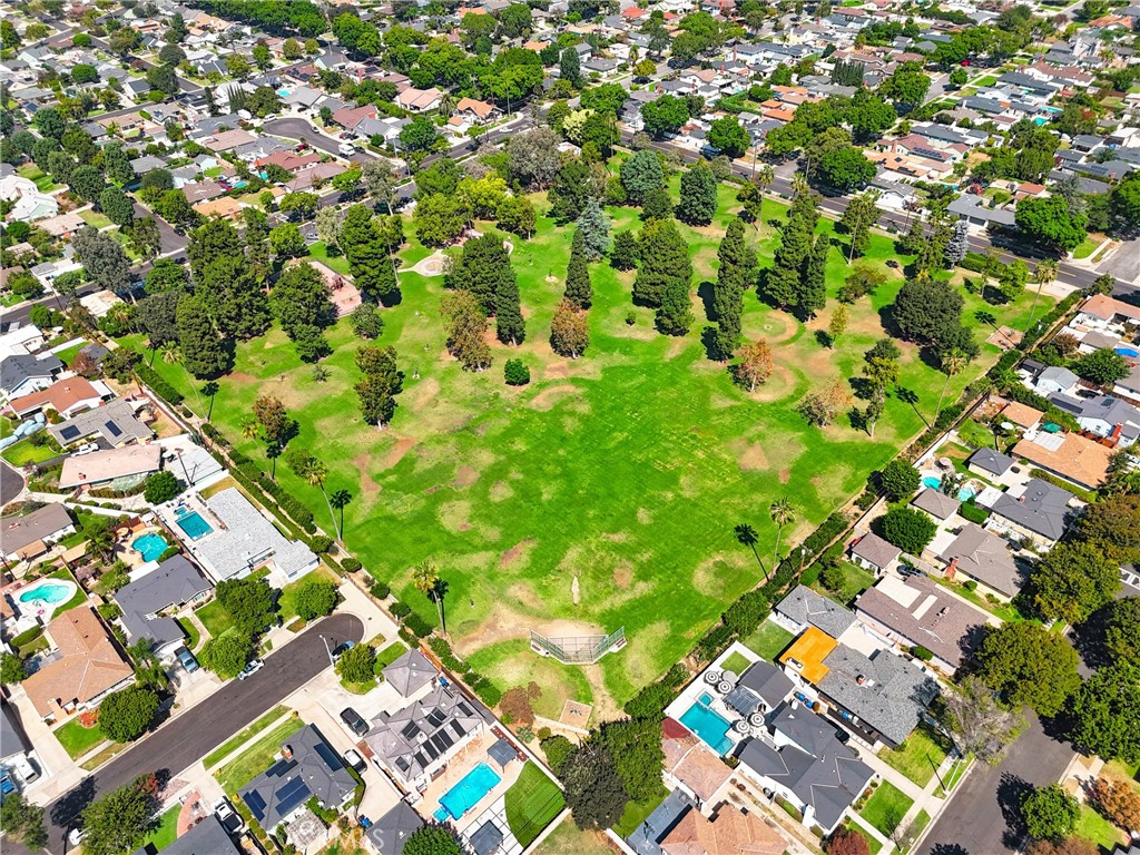 Aerial view of a tree-filled grassy park surrounded by homes.