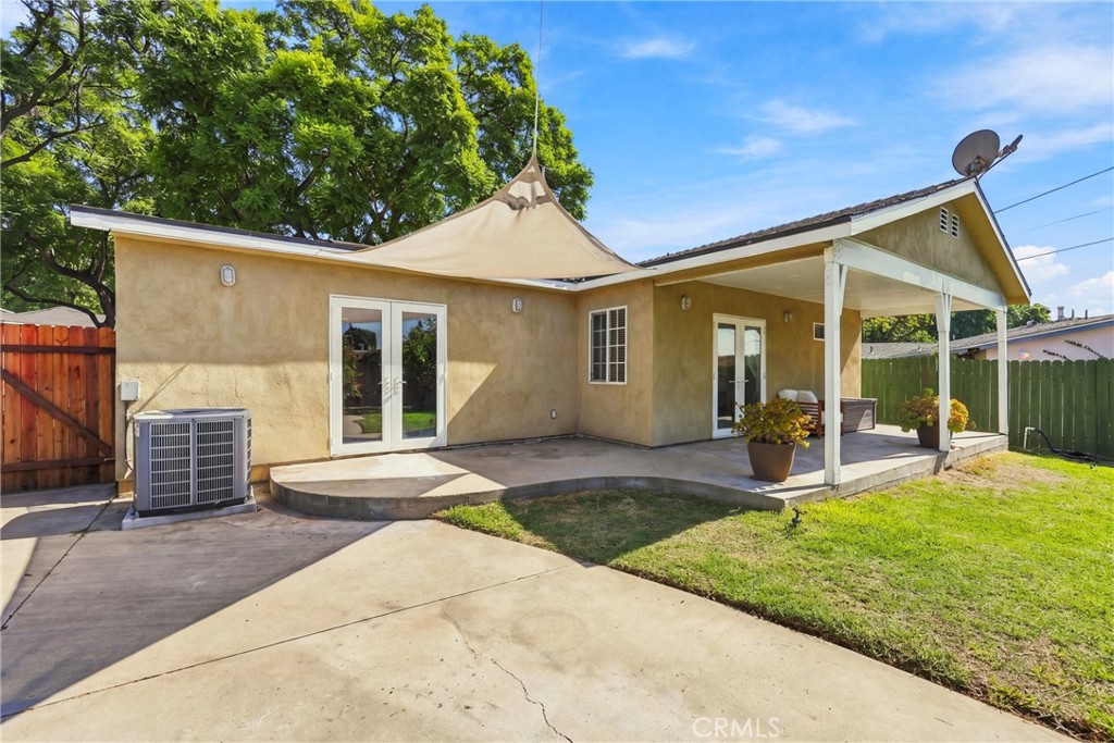 Rear patio with covered seating area, shade sail, concrete courtyard, and lawn.
