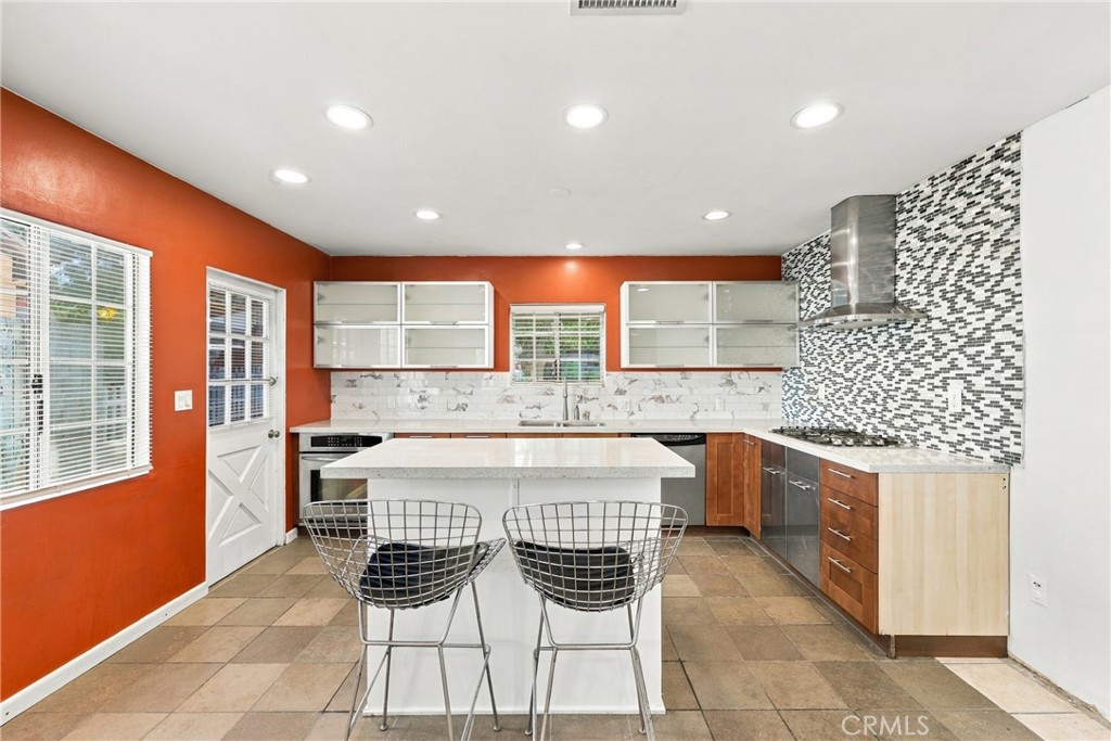 Kitchen with a white island, orange walls, and patterned tile backsplash.