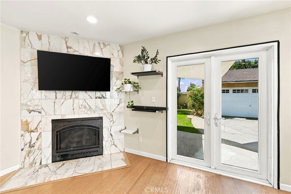 Living room with a marble fireplace wall, mounted TV, and glass doors to the yard.