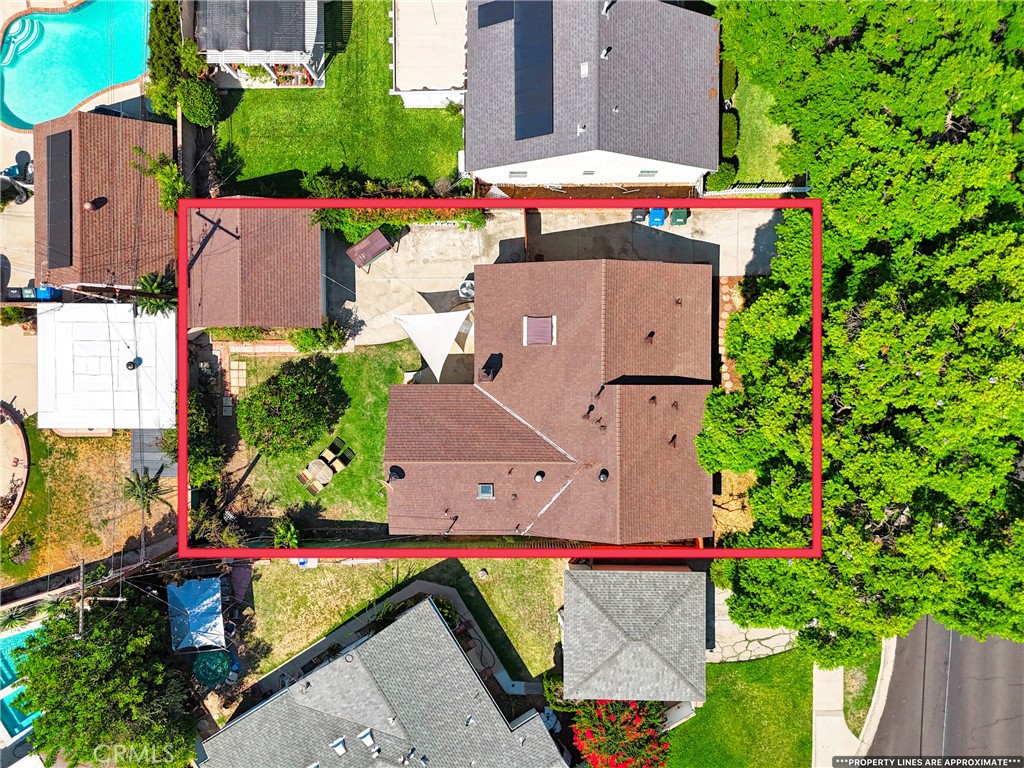 Aerial view of the property outlined in red, showing its roof, yard, and driveway.