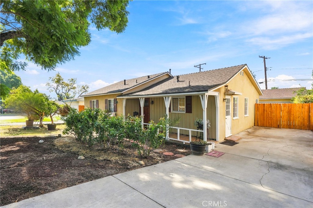 Single-story yellow house with a covered porch, front garden, and concrete driveway.