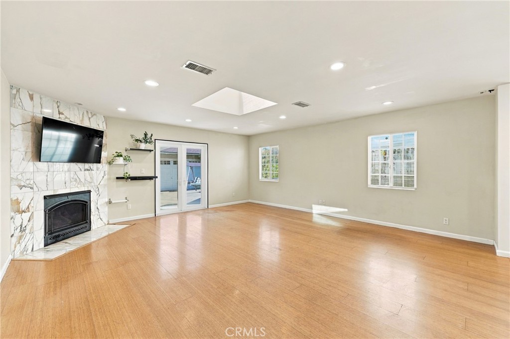 Living room with hardwood floors, a marble fireplace, and sliding glass doors.