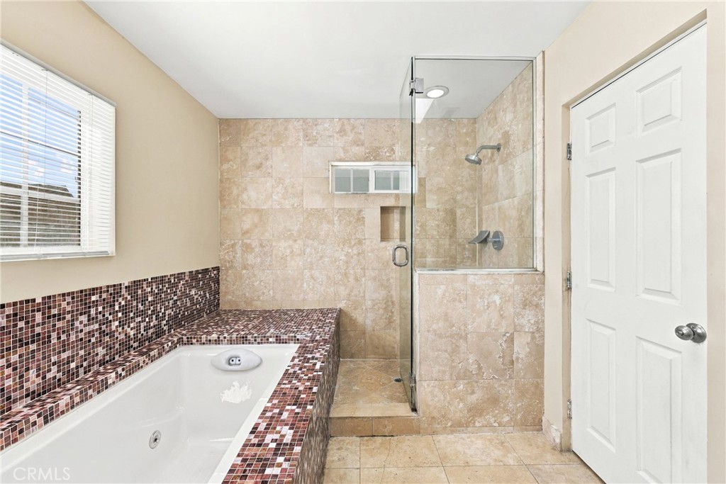 Bathroom with a tiled soaking tub beside a glass-enclosed shower.