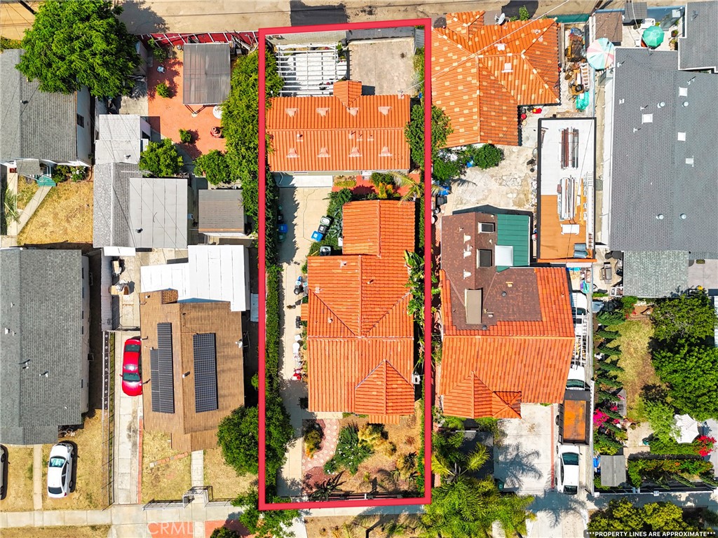 Aerial view of the home and lot, outlined in red, with terracotta tile roofs and neighboring houses.