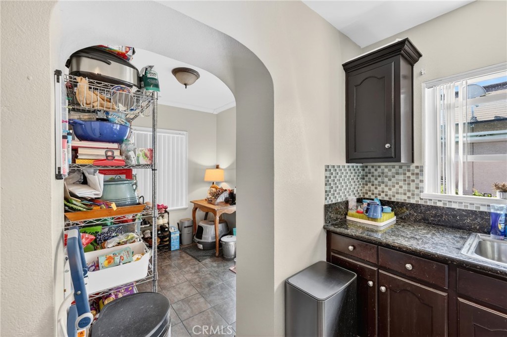 Kitchen with dark wood cabinets and granite counters, opening through an arch to a pantry nook.
