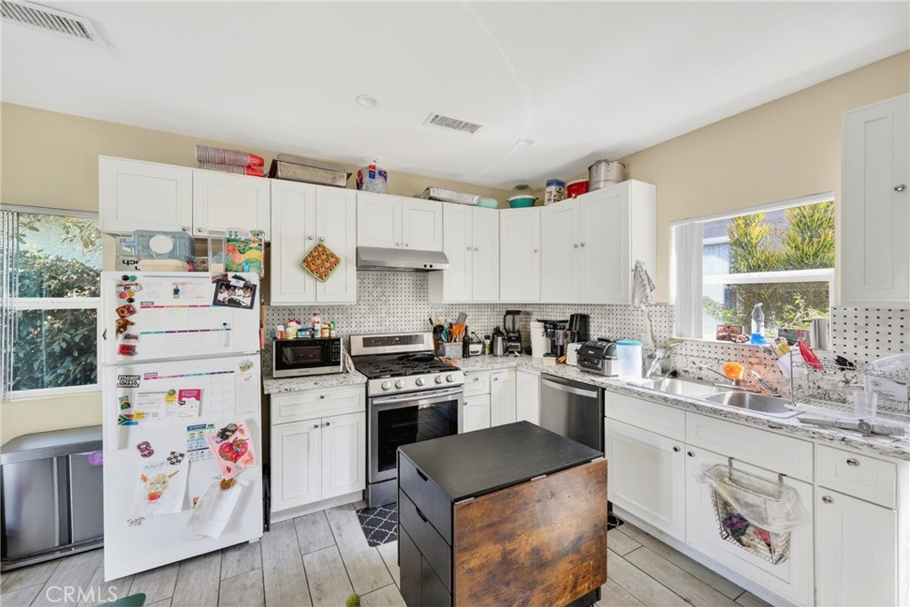 Kitchen with white cabinets, stainless appliances, and a dark-topped wood island.