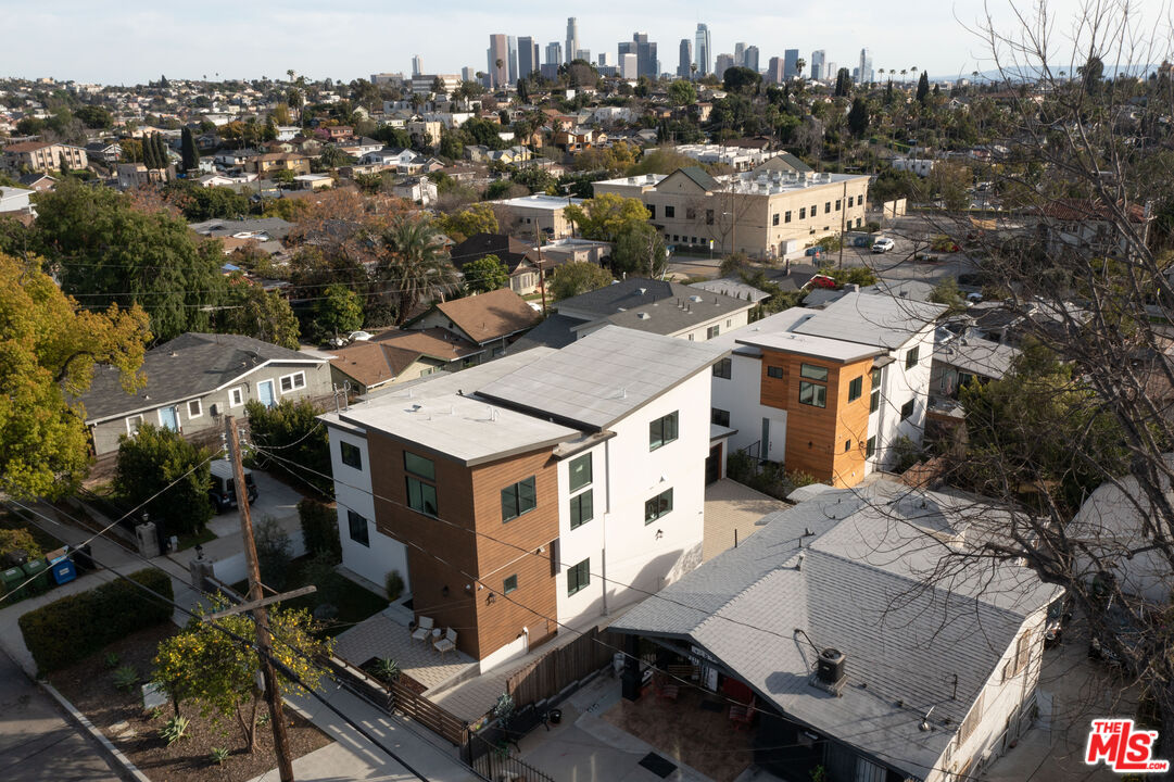 Modern white and wood-clad homes viewed from above, with the downtown Los Angeles skyline in the distance.