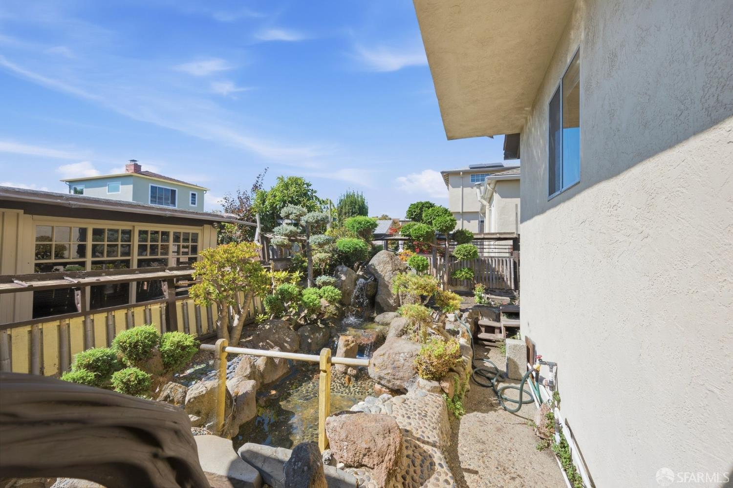 Landscaped side yard with a rock-lined pond and water feature beside the house.