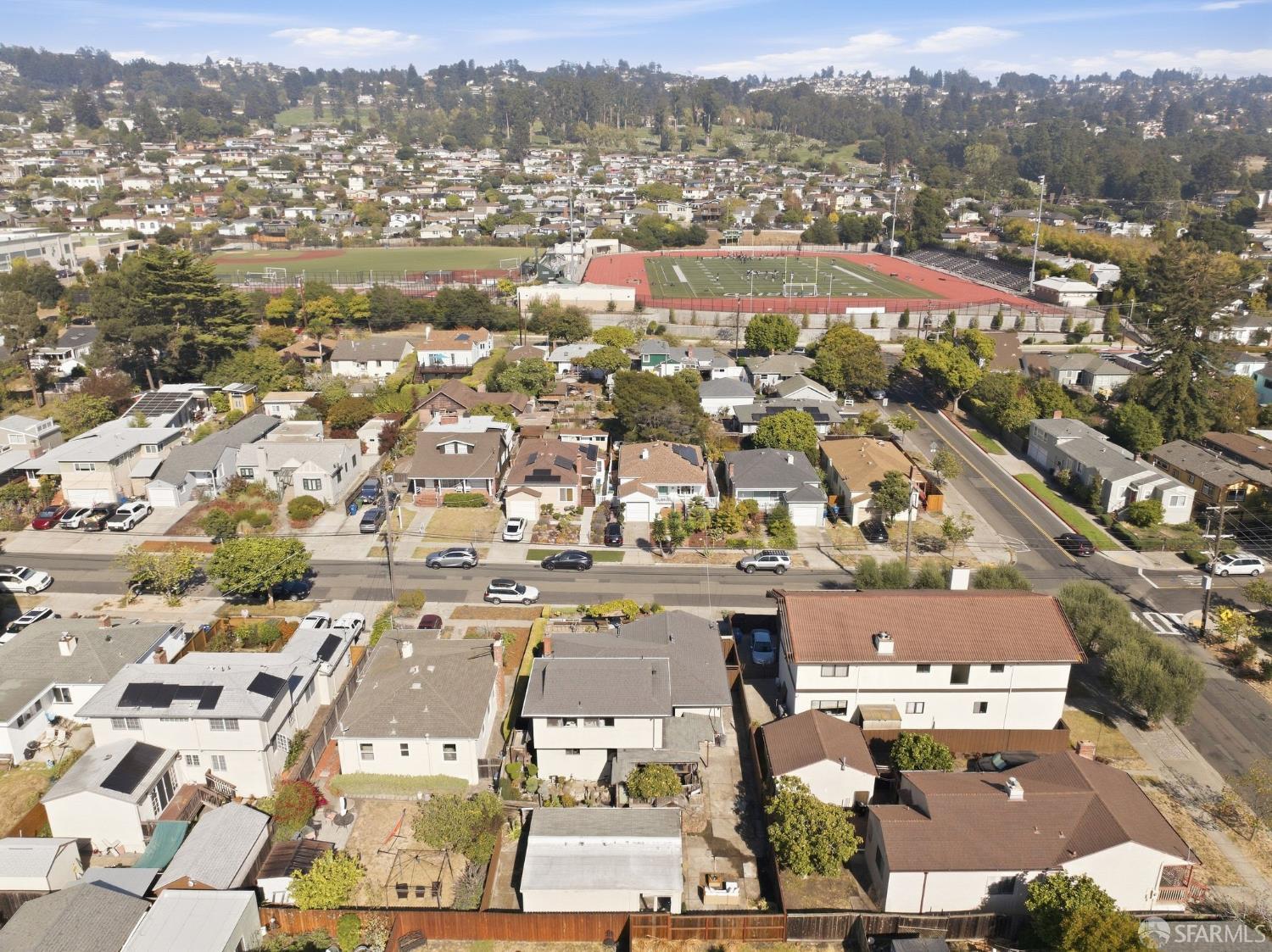 Aerial view of El Cerrito homes, an athletic field and track, and wooded hills.