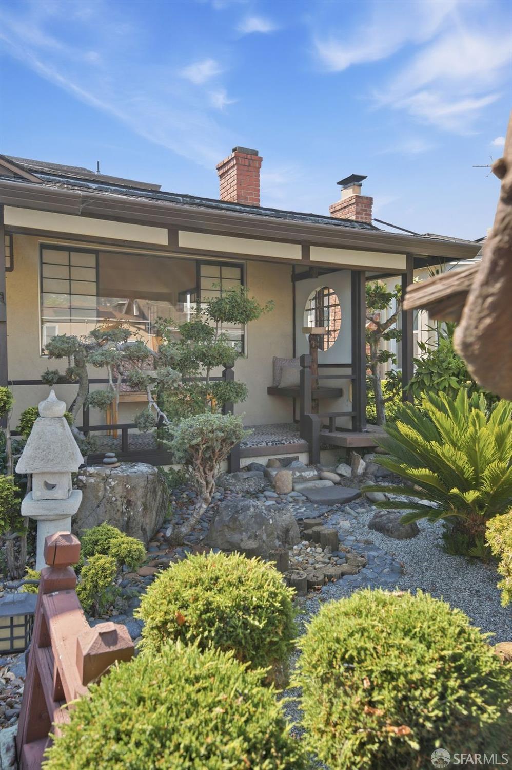 Home exterior with a Japanese-style rock garden, stone lantern, and covered courtyard seating.