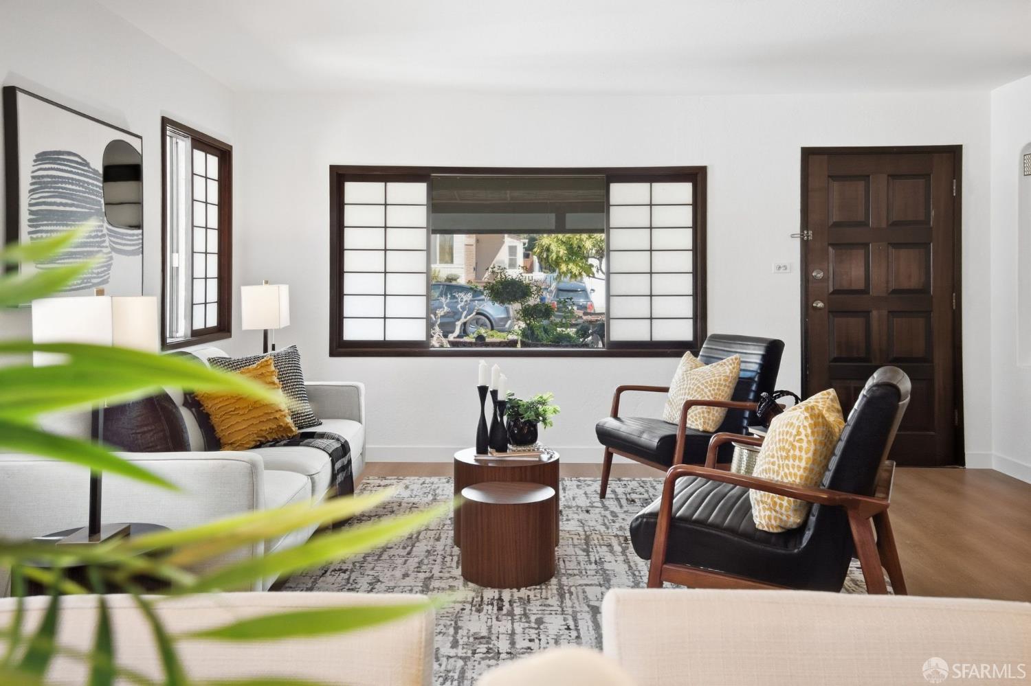 Living room with shoji-style window panels, dark wood trim, and a mix of white and black seating.
